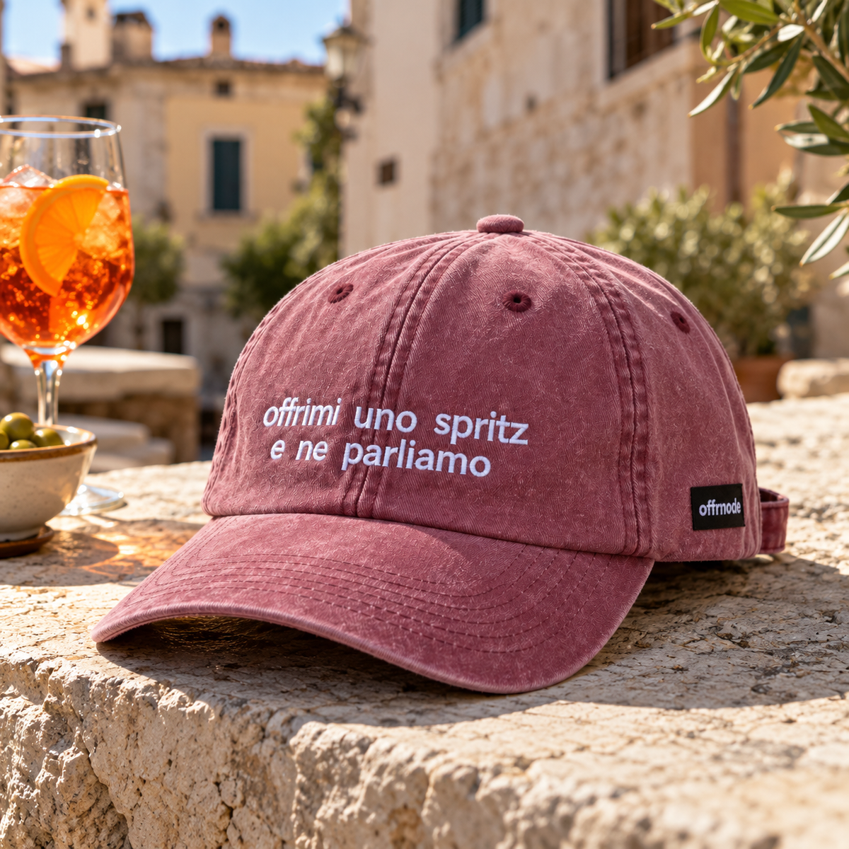 Cappello bordeaux Offmode con la frase "offrimi uno spritz e ne parliamo" ricamata durante un aperitivo con spritz